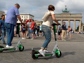 People use electric scooters by California-based bicycle rental service Lime at the Brandenburg Gate in Berlin, Germany, June 21, 2019. (REUTERS/Fabrizio Bensch)