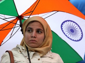 A spectator with an umbrella waits out a rain delay during the Cricket World Cup semifinal between India and New Zealand in Manchester, England, on July 9, 2019. (LEE SMITH/Reuters)