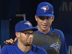 Toronto Blue Jays pitcher Ryan Borucki (right) pats former teammate Eric Sogard on the shoulder in the dugout after learning that Sogard had been traded in mid-game to the Tampa Bay Rays on July 28, 2019. (DAN HAMILTON/USA TODAY Sports)