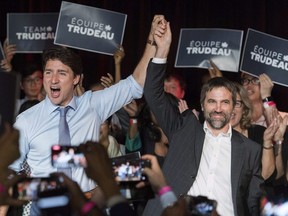 Canadian Prime Minister Justin Trudeau, left, raises the hand of Steven Guilbeault during an event to launch his candidacy for the Liberal Party of Canada in Montreal, Wednesday, July 10, 2019.