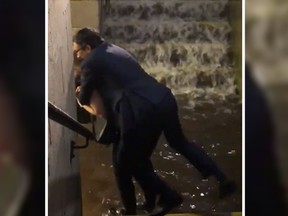 In a viral video, a suit-wearing man is seen being piggy-backed by a woman to escape flooding at a New Jersey train station. (Twitter)
