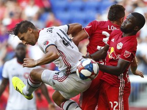 Toronto FC's Omar Gonzales defends against New York Red Bulls midfielder Aaron Long and defender Kemar Lawrence during Saturday's game/ (USA TODAY SPORTS)