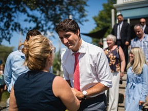 Prime Minister Justin Trudeau greets a guest at a local cafe alongside Kings-Hants Liberal Party candidate Kody Blois, left obscured, in Elmsdale, N.S., on Friday, Aug. 16, 2019.