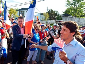 Prime Minister Justin Trudeau points to Conservative Leader Andrew Scheer while walking with the crowd during the Tintamarre in celebration of the National Acadian Day and World Acadian Congress in Dieppe, N.B., on Aug. 15, 2019.