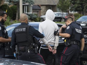 Toronto Police officers are pictured executing a a high-risk takedown on O'Connor Dr. on Aug. 9, 2019, in which officers seized guns. (Stan Behal, Toronto Sun)