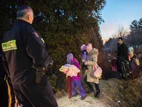 RCMP officers look on as an extended family of seven people from Turkey illegally cross the US-Canada border just before dawn on February 28, 2017 near Hemmingford, Quebec.