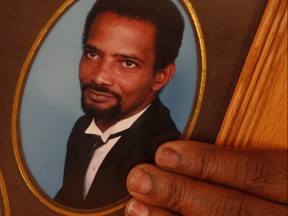 The wife of Glensbert "Sam" Oliver, 63, stabbed to death outside of his Brampton home Aug. 2,  holds a photo of her slain husband. Peel police are still searching for the killer, one of a group of people he caught breaking into his car.