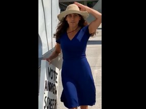 A woman holding a Vote Andrew Scheer sign was captured on video outside Toronto City Hall spitting on a man.