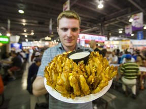 Toronto Sun reporter Aidan Wallace poses with the deep fried Colossal Onion at the Food Building at the annual CNE in Toronto, Ont.  on Saturday August 17, 2019.