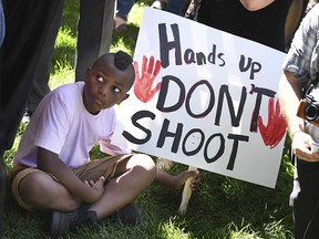 A protester holds a sign at a news conference in front of the Colorado Springs Police Department Police Operations Center, Tuesday, Aug. 13, 2019, in Colorado Springs, Colo. (Jerilee Bennett/The Gazette via AP)