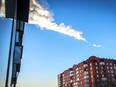 A meteorite trail is seen above a residential apartment block in the Urals city of Chelyabinsk, on February 15, 2013. A heavy meteor shower rained down today on central Russia, sowing panic as the hurtling space debris smashed windows and injured dozens of stunned locals, officials said.