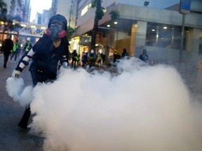 An anti-extradition bill protester throws a tear gas cartridge back at police during clashes in Wan Chai in Hong Kong, China, on Sunday, Aug. 11, 2019.