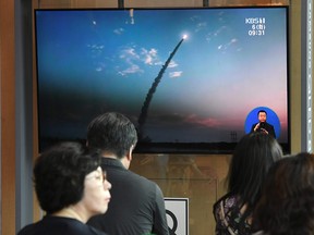 People watch a television news screen showing a file footage of North Korea's missile launch, at a railway station in Seoul on Aug. 6, 2019.