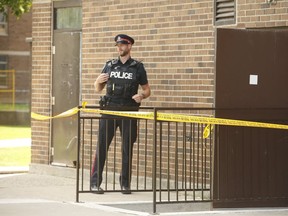 A Toronto Police officer stands guard near a stairwell entrance to a highrise at 30 Falstaff Ave. Homicide investigators were called to the building for a early morning shooting in which a 16-year-old resident Hanad Abdullahi was found shot in a stairwell on Thursday, Aug. 1, 2019. (Jack Boland/Toronto Sun/Postmedia Network)