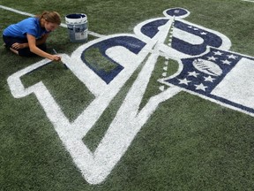 Laurel Gray paints an NFL logo onto IG Field in Winnipeg on Wednesday, Aug. 21, 2019 in advance of Thursday's NFL exhibition clash between the Oakland Raiders and the Green Bay Packers.