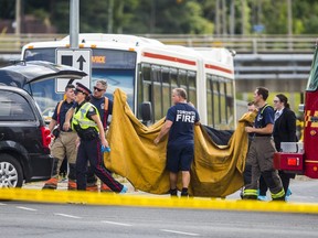 Emergency personnel obscure the gurney containing the remains of a female senior citizen run down by two vehicles at Midland and Sheppard Aves. on Wednesday. Both vehicles fled the scene