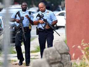 Police officers carrying assault rifles respond to a shooting on Aug. 14, 2019 in Philadelphia, Pa.