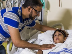 Ruhul Chowdhury at the bedside of his son Radi, 4 -- the victim of a motorcycle hit-and-run three months ago in Scarborough -- at The Hospital for Sick Children in Toronto, Ont. on Wednesday. Aug. 21, 2019. (Ernest Doroszuk/Toronto Sun/Postmedia)