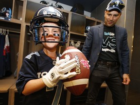 Darius Raso, a seven-year-old boy from Kleinburg, Ont. who has been battling acute lymphocytic leukemia for the past year, signed a one-day contract with the Toronto Argonauts and is seen here with his dad, Marc, in the team's locker room on Thursday, Aug. 29, 2019. (Jack Boland/Toronto Sun/Postmedia Network)