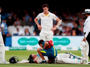Australia’s Steve Smith receives treatment as he lays on the floor after being hit by a ball from England’s Jofra Archer as England’s Jos Buttler and Australia’s Pat Cummins look on.  Reuters