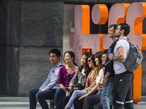 People pose by the TIFF sign on Festival St. -- King St., between University Ave. and Peter St., on Sept. 6, 2019. (ERNEST DOROSZUK, Toronto Sun)