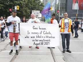 Clayton Jones (left) and another man carry a sign dedicated to Jones' sister, Celeste, who was killed in a hit-and-run collision in Scarborough. (Jack Boland, Toronto Sun)