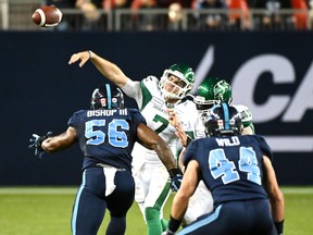 Roughriders quarterback Cody Fajardo gets a pass away with Freddie Bishop and Ian Wild of the Argos closing in during last night’s game at BMO Field.                                                       Jon Blacker/CP