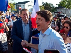 Prime Minister Justin Trudeau shakes hands with Conservative Leader Andrew Scheer while walking with the crowd during the Tintamarre in celebration of the National Acadian Day and World Acadian Congress in Dieppe, N.B., Thursday, Aug. 15, 2019.