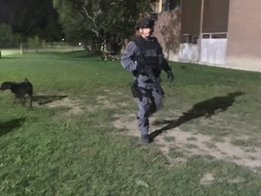 A heavily armed police officer patrols around a building following a shooting that left one teen dead and four other people injured. (Joe Warmington, Toronto Sun)