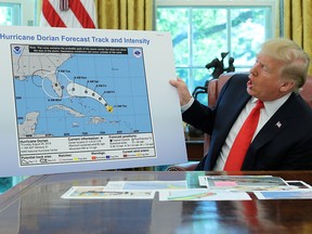 President Donald Trump holds a chart showing the original projected track of Hurricane Dorian that appears to have been extended with a black line to include parts of the Florida panhandle and of the state of Alabama during a status report meeting on the hurricane in the Oval Office of the White House in Washington, U.S., September 4, 2019. (REUTERS/Jonathan Ernst)