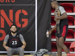 Toronto Raptors' Fred Van Vleet (left) smiles as teammate Serge Ibaka carries an championship belt during training camp on Wednesday. (THE CANADIAN PRESS)