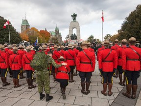 A mountie is overcome and takes a knee during a memorial service at the National War Memorial during the one-year anniversary of the Oct. 22, 2014 attacks on Parliament Hill and at the Cenotaph.  The event honoured the sacrifices of Warrant Officer Patrice Vincent and Corporal Nathan Cirillo, and the bravery of the first responders.