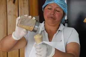 In this Sept. 28, 2019 photo, Maria del Carmen Pilapana tops a scoop of a guinea pig-flavoured ice cream with peanuts at her stall on the outskirts of Quito, Ecuador.