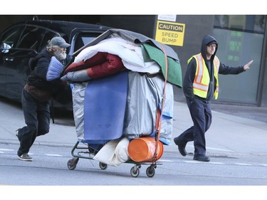 A homeless man removes his belongings after city workers clear out those living on Lower Simcoe Street in Toronto on Friday, October 4, 2019. Veronica Henri/Toronto Sun/Postmedia Network