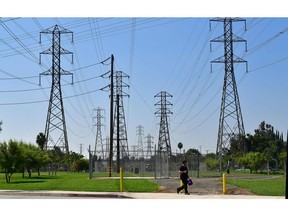 A pedestrian walks past a row of power lines in Rosemead, California on October 9, 2019, as southern California braces for the possibility of widespread power outages.