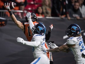 B.C. Lions' Bryan Burnham, back left, makes a one-handed catch in the end zone to score his second touchdown as Toronto Argonauts Trumaine Washington, front left, and Anthony Covington, right, defend in Vancouver, Saturday, Oct. 5, 2019. (THE CANADIAN PRESS/Darryl Dyck)