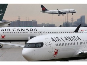 Two Air Canada Boeing 737 MAX 8 aircrafts are seen on the ground as Air Canada Embraer aircraft flies in the background at Toronto Pearson International Airport in Toronto, Ontario, Canada, March 13, 2019.