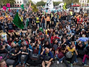 Protesters sit on the ground to block the Pont au Change bridge during a demonstration called by climate change activist group Extinction Rebellion, in Paris on Monday, Oct. 7, 2019.
