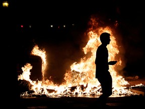 A demonstrator walks past a fire during a protest after a verdict in a trial over a banned Catalonia's independence referendum in Barcelona, Spain, October 16, 2019. (REUTERS/Albert Gea)