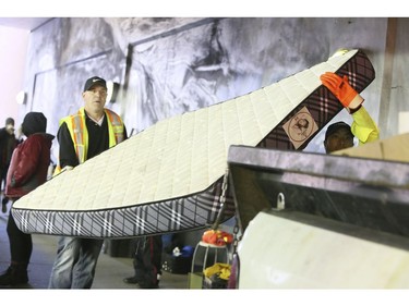 Workers remove a mattress that once formed the basis for a makeshift tent for a homeless man living on Lower Simcoe Street in Toronto on Friday, October 4, 2019. Veronica Henri/Toronto Sun/Postmedia Network