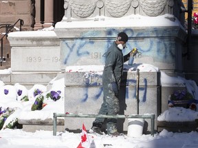 A worker cleans graffiti from Old City Hall cenotaph in Toronto on Tuesday, November 12, 2019. Craig Robertson/Toronto Sun