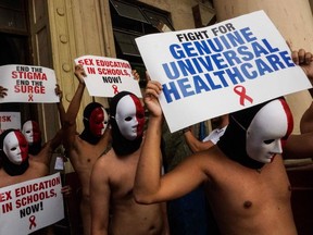 Nude members of a fraternity hold placards as they participate in an "Oblation Run" at the University of the Philippines campus in Manila on November 29, 2019. - The annual event, which includes a nude run, was used to draw the attention to HIV/AIDS issues in the Philippines, which has a rapidly growing HIV epidemic, with rights groups saying the government has failed to promote contraceptives and give sex education to gay or bisexual men. (Photo by DANTE DIOSINA JR / AFP)