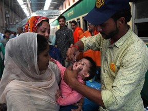 A Pakistani health worker administers polio drops to a child at a railway station during a polio vaccination campaign in Lahore on November 5, 2019.