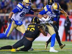 Andrew Harris of the Winnipeg Blue Bombers avoids a tackle from Hamilton Tiger-Cats Cariel Brooks during the 107th Grey Cup CFL championship football game in Calgary on Sunday, November 24, 2019. Al Charest/Postmedia