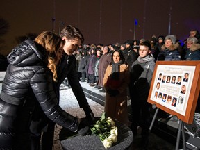 Prime Minister Justin Trudeau and his wife Sophie Gregoire Trudeau lay white roses in front of a photo showing the 14 women who were killed during a vigil on top of Mount Royal marking the thirtieth anniversary of the mass shooting at Ecole Polytechnique, Dec. 6, 2019.  (REUTERS/Christinne Muschi)