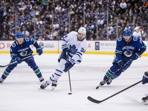 Toronto Maple Leafs' Auston Matthews (34) skates with the puck while being watched by Vancouver Canucks' Brock Boeser, back left, Josh Leivo, back right, during third period NHL hockey action in Vancouver on March 6, 2019. THE CANADIAN PRESS/Darryl Dyck