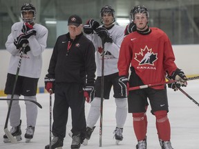 Head coach Dale Hunter watches his charges at yesterday’s practice along with (from left) forwards Quinton Byfield, Dylan Cozens and Alexis Lafreniere. Canada takes on Russia in a preliminary-round game this afternoon.  Ryan Remiorz/CP