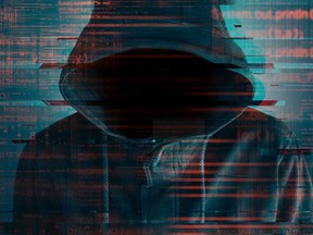 Cybersecurity, computer hacker with hoodie and obscured face, computer code overlaying image