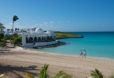 A couple walks on the beach at the Belmond Cap Juluca Resort in Anguilla