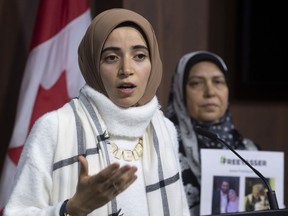Safaa Eleshmawy (right), wife of Yasser Albaz, currently detained in Egypt, looks on as his daughter Amal Ahmed holds up a petition for his release during a news conference, Wednesday, Dec. 11, 2019 in Ottawa.